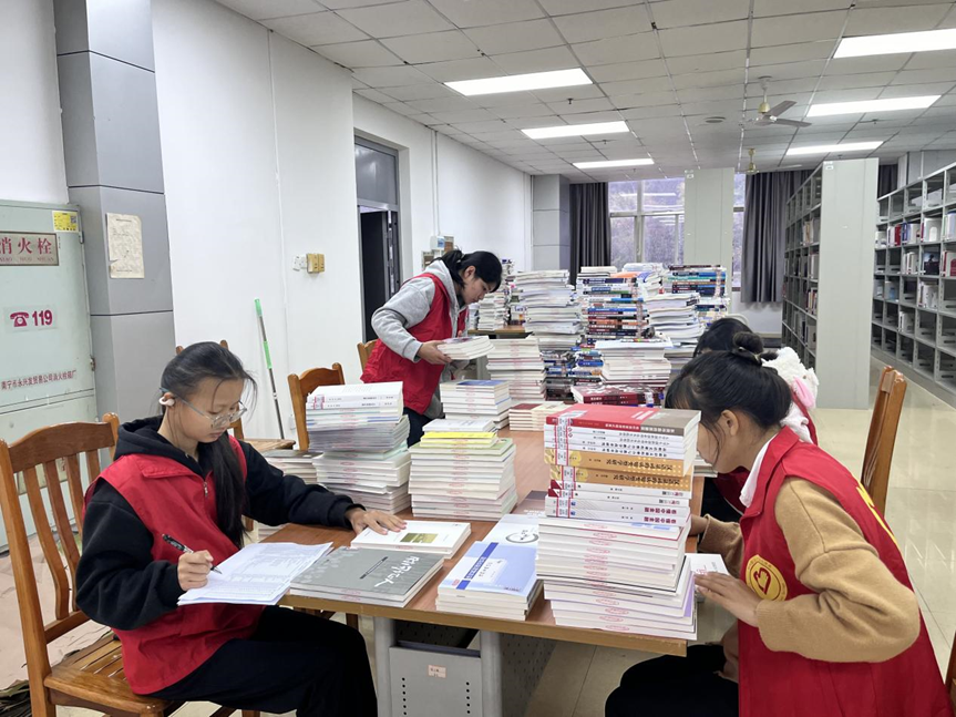 志愿者们在学校图书馆为新书编码、登记入库